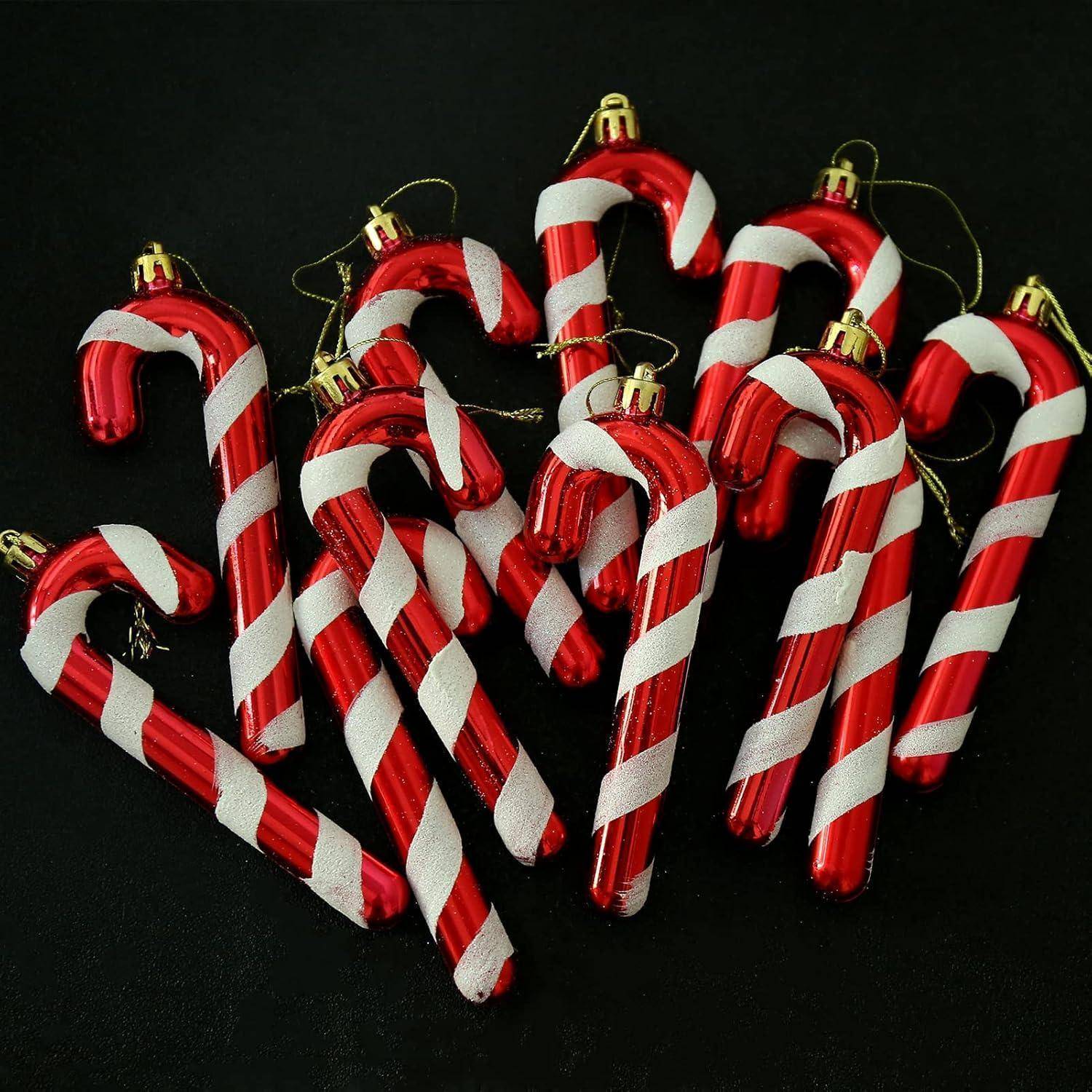 „Rot-weiß gestreifte Zuckerstangen-Anhänger auf einem dunklen Hintergrund, zufällig angeordnet, mit goldenen Schlaufen zum Aufhängen als Dekorationen.