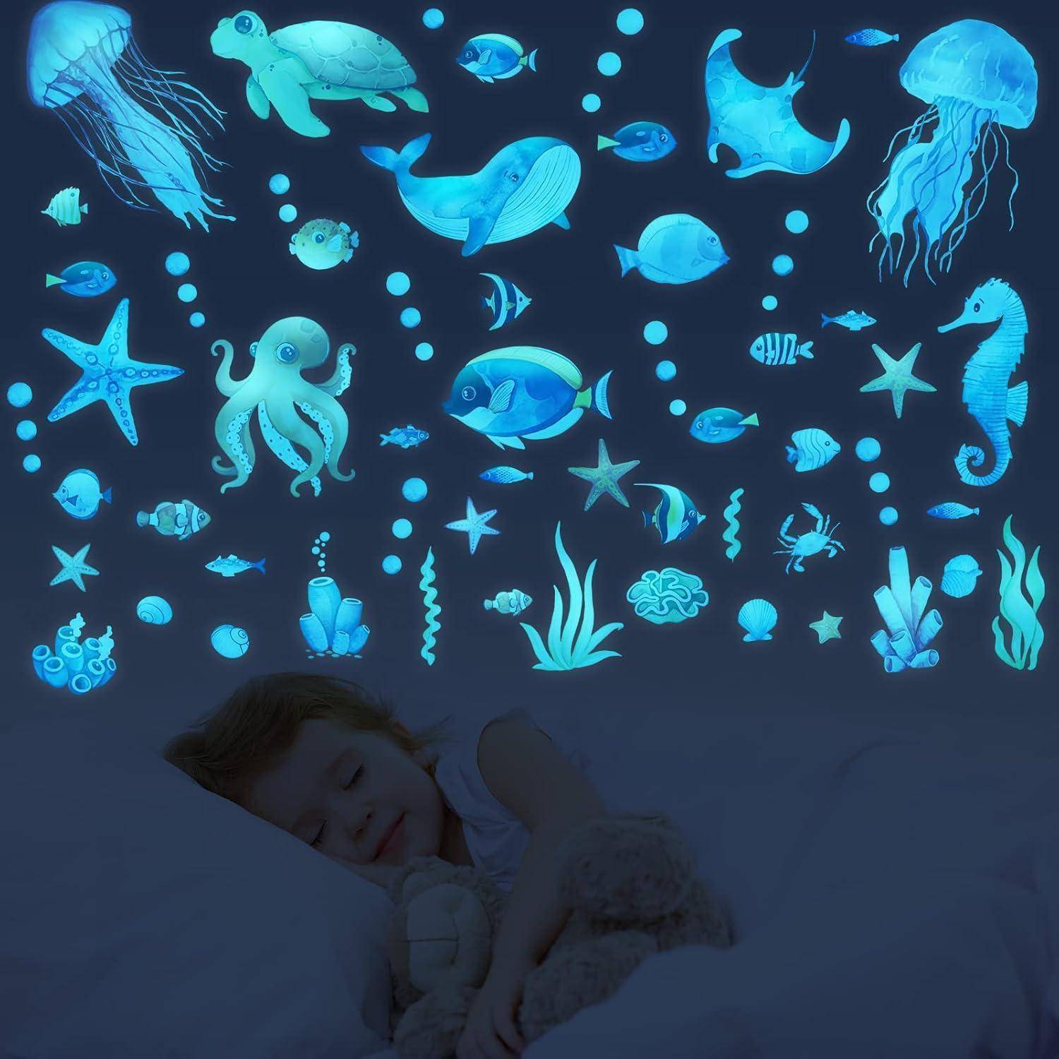 Ein Kind schläft friedlich mit einem Stofftier, umgeben von leuchtenden Illustrationen von Meeresbewohnern an der Wand, die eine traumhafte Unterwasserstimmung erschaffen.