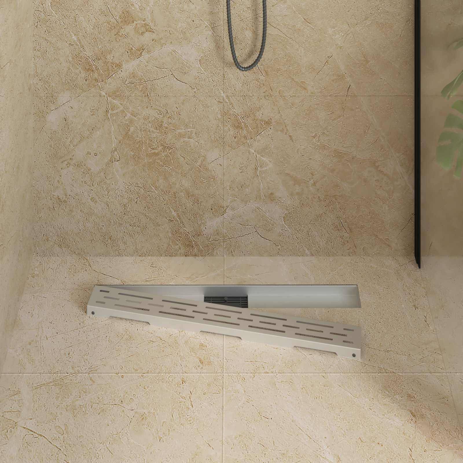 Eine beige geflieste Duschbodenablage mit einem linearen Ablauf und einem metallenen Duschschlauch, der herunter hängt und teilweise zu sehen ist.