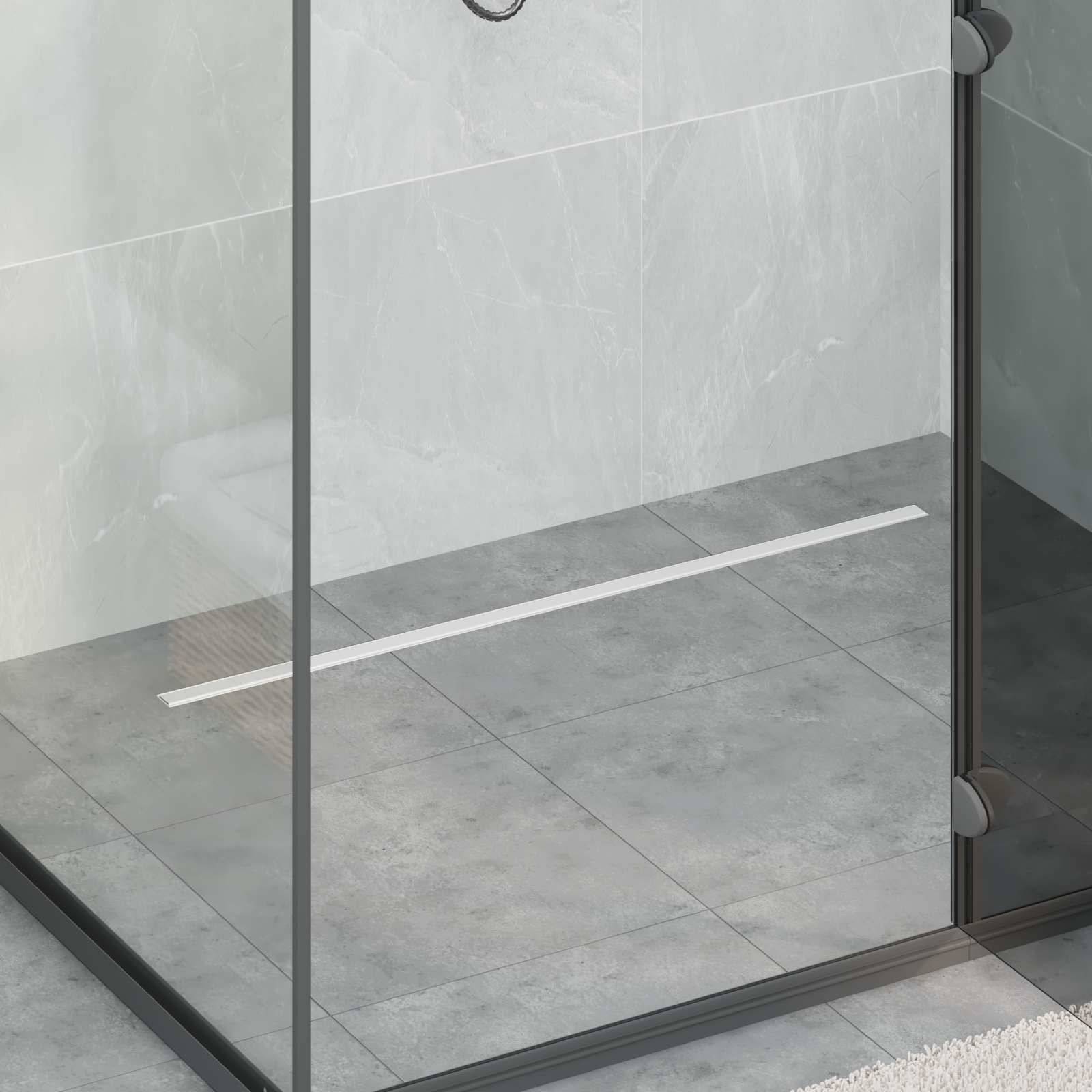 Eine Duschzone mit Glasscheiben und gefliester Wand, mit mattschwarzem Rahmen und einem linearen Ablauf auf einem strukturierten grauen Bodenfliesen.