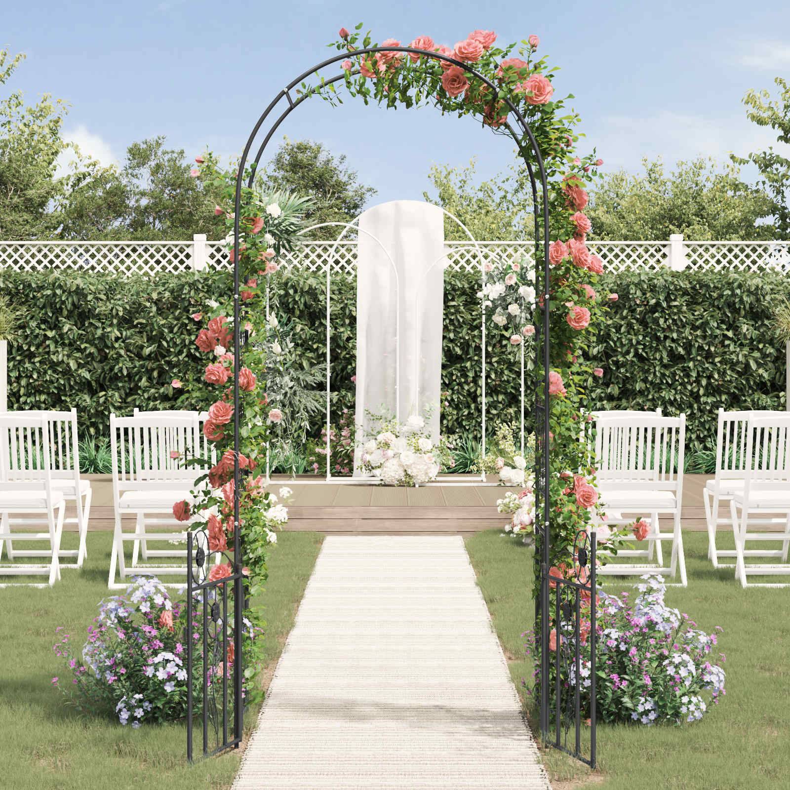 Eine Hochzeitskulisse im Freien mit einem Blumenbogen, weißen Stühlen auf beiden Seiten und einem Weg, der zu einem von Grünpflanzen umgebenen Altar führt.