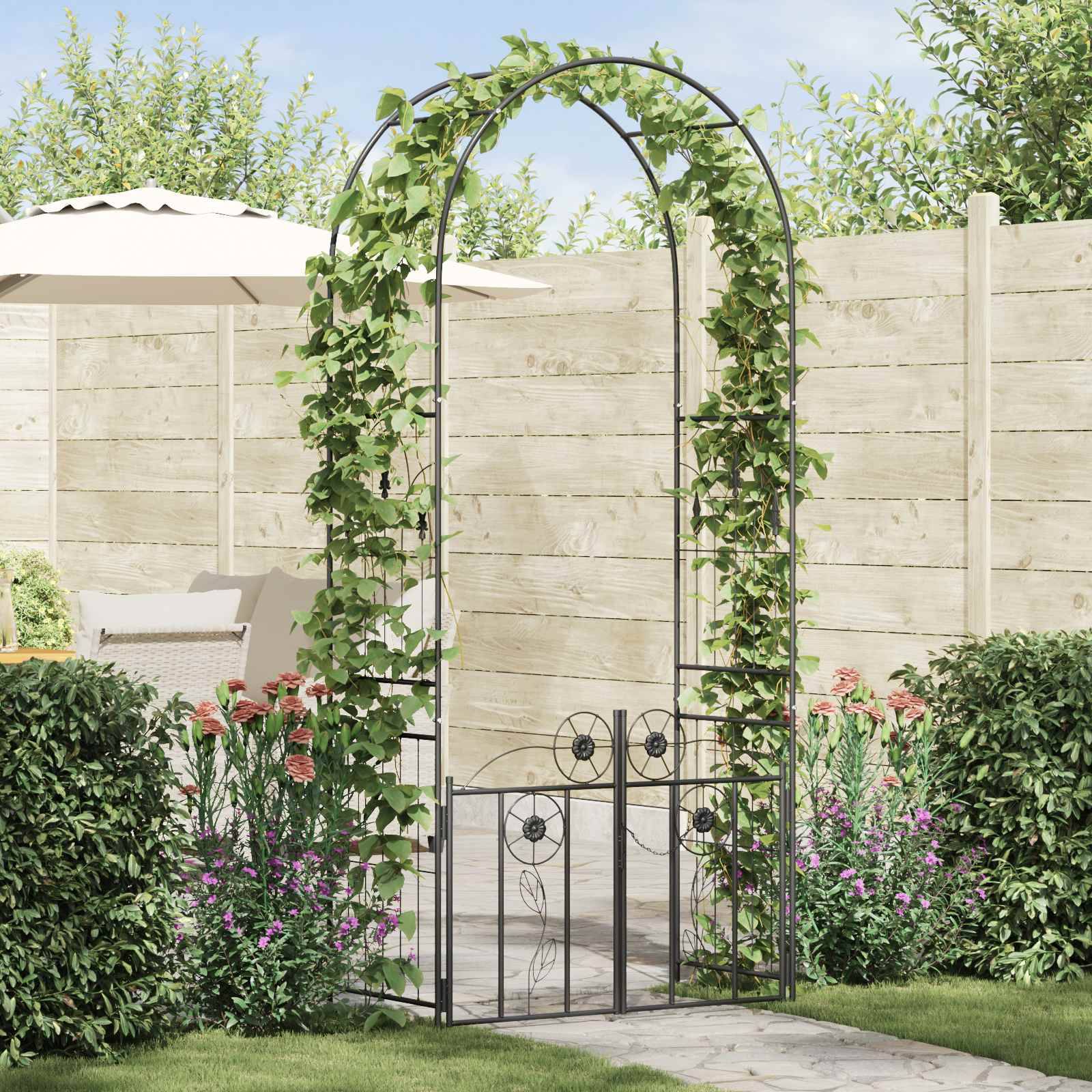Ein Gartenbogen mit Kletterpflanzen, umgeben von bunten Blumen und Grünpflanzen, führt zu einem Holzzaun. Eine Terrasse mit einem Sonnenschirm ist zu sehen.