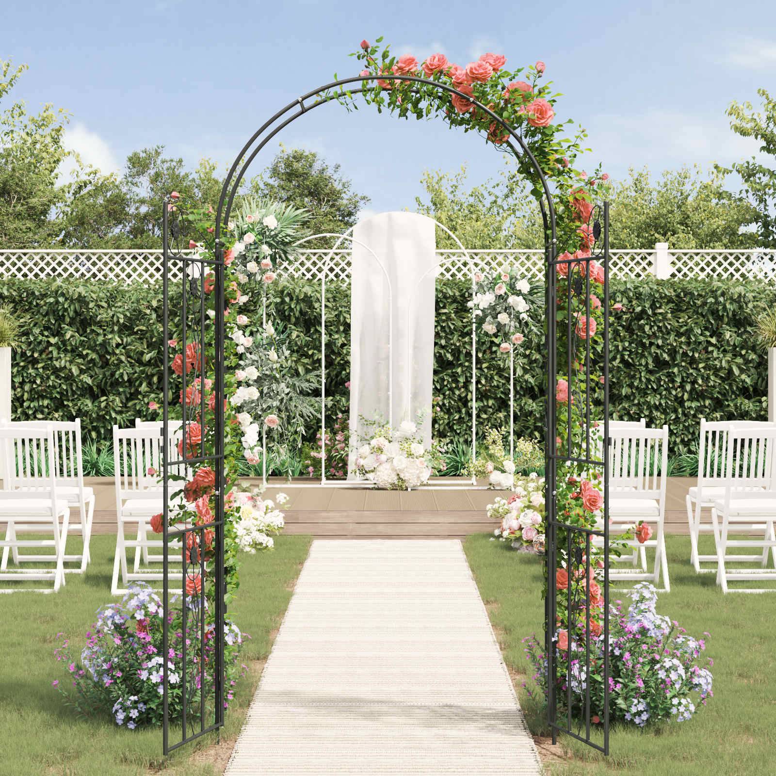Eine Gartenhochzeitskulisse mit einem Blumenbogen aus rosa und weißen Blumen, einem weißen Gangläufer und weißen Stühlen, die auf grünem Rasen angeordnet sind.