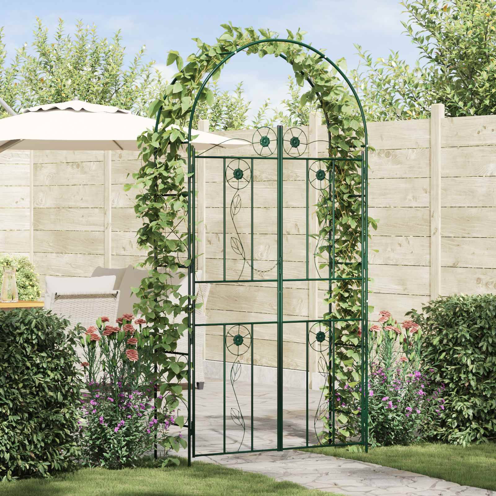 Eine Gartenszene mit einem Metallbogen, der mit Grünpflanzen bewachsen ist und zu einer Terrassenanlage führt, die von einem Holzzaun, einem Sonnenschirm und verschiedenen Pflanzen umgeben ist.
