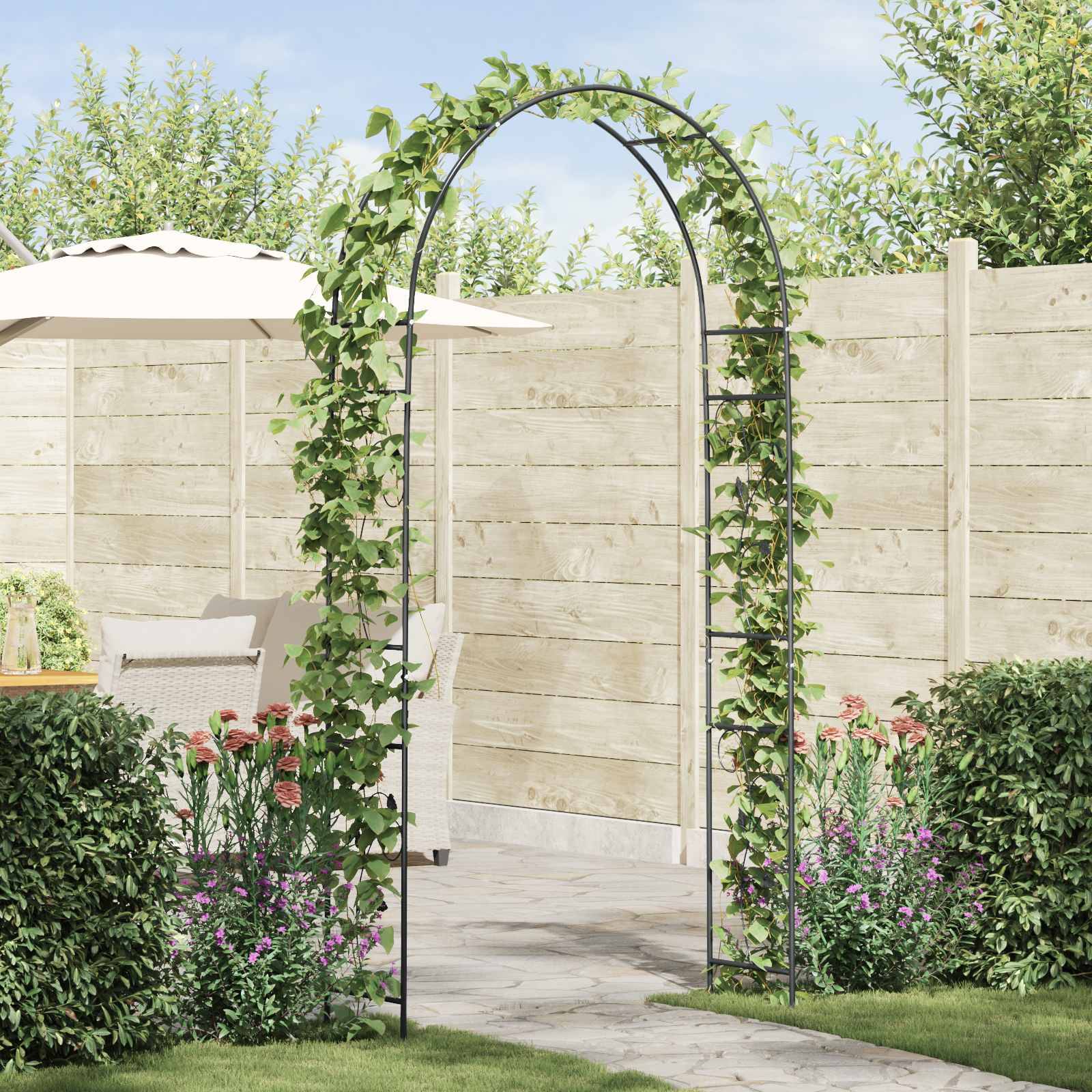 Gewölbtes Gartengerüst mit Kletterranken, umgeben von farbenfrohen Blumen. Der Hintergrund zeigt einen Holzzaun und Terrassenmöbel.