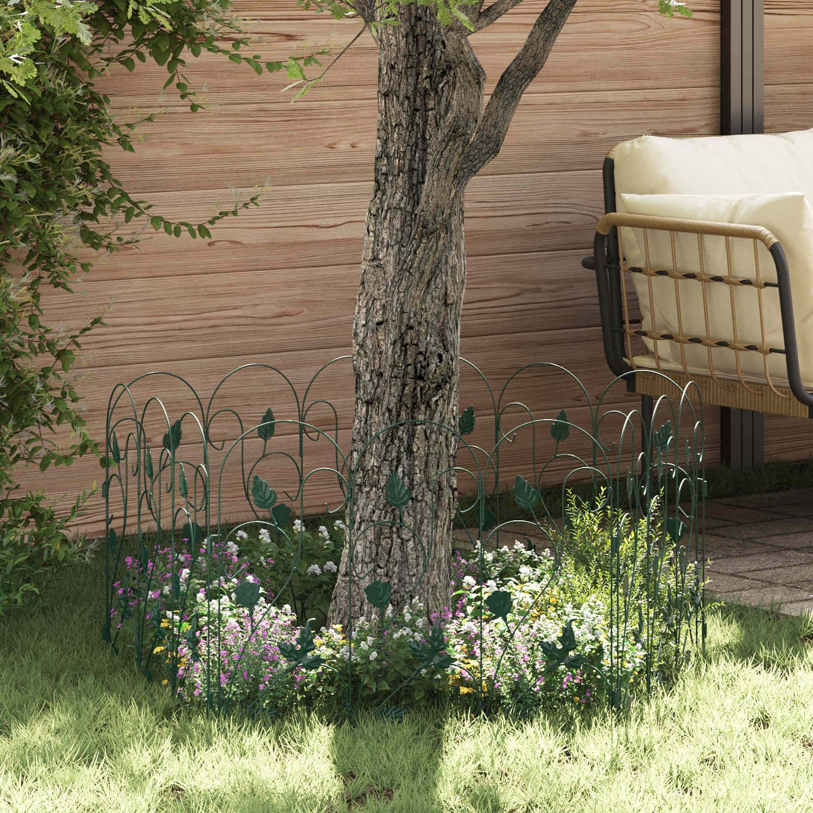 Ein Baumstamm, umgeben von einem kleinen dekorativen Zaun in einem Garten mit grünem Gras und einer Holzbank neben einer Holzwand.