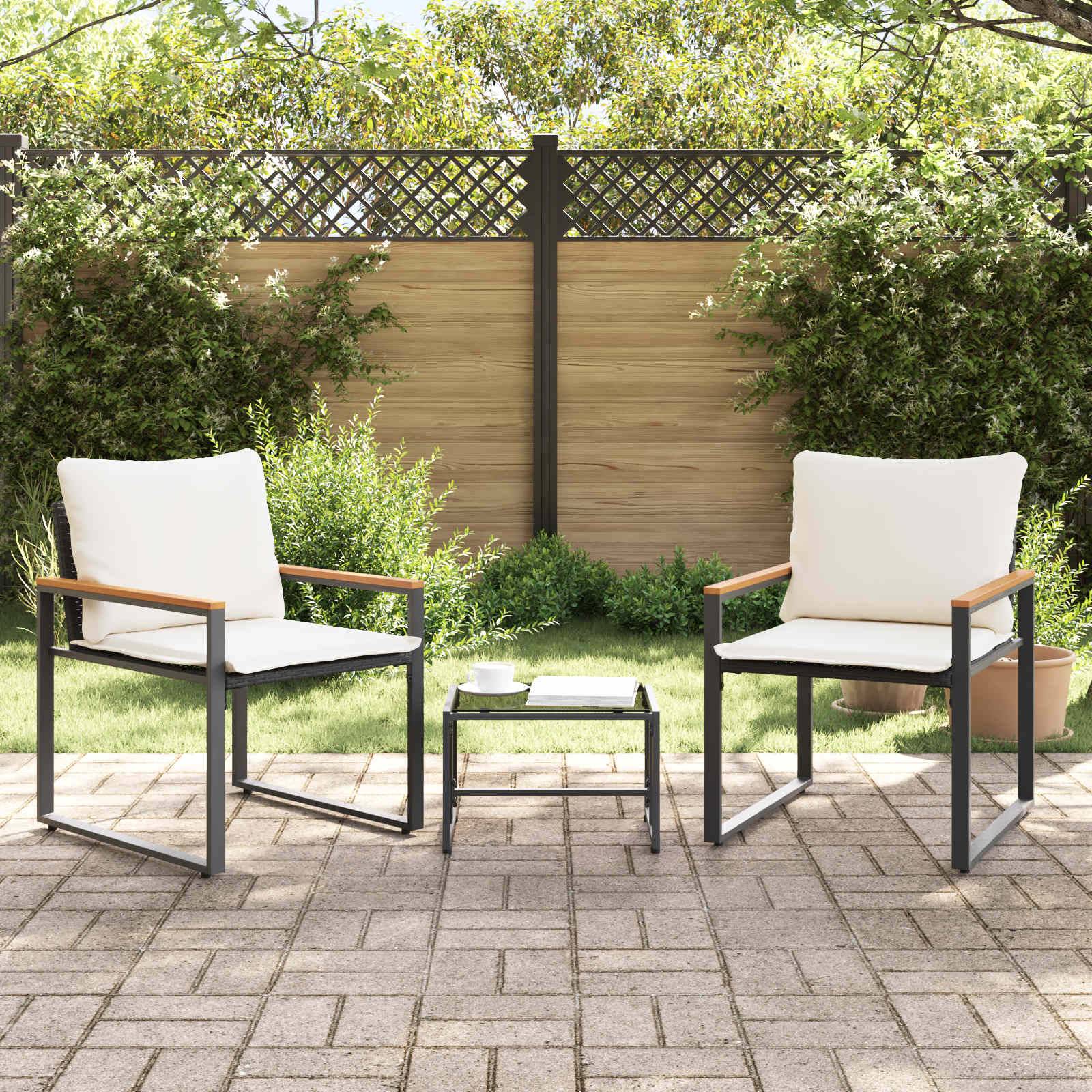 Zwei weiß gepolsterte Terrassenstühle mit einem kleinen schwarzen Tisch zwischen ihnen, platziert auf einer gefliesten Terrasse, umgeben von üppigen grünen Sträuchern.