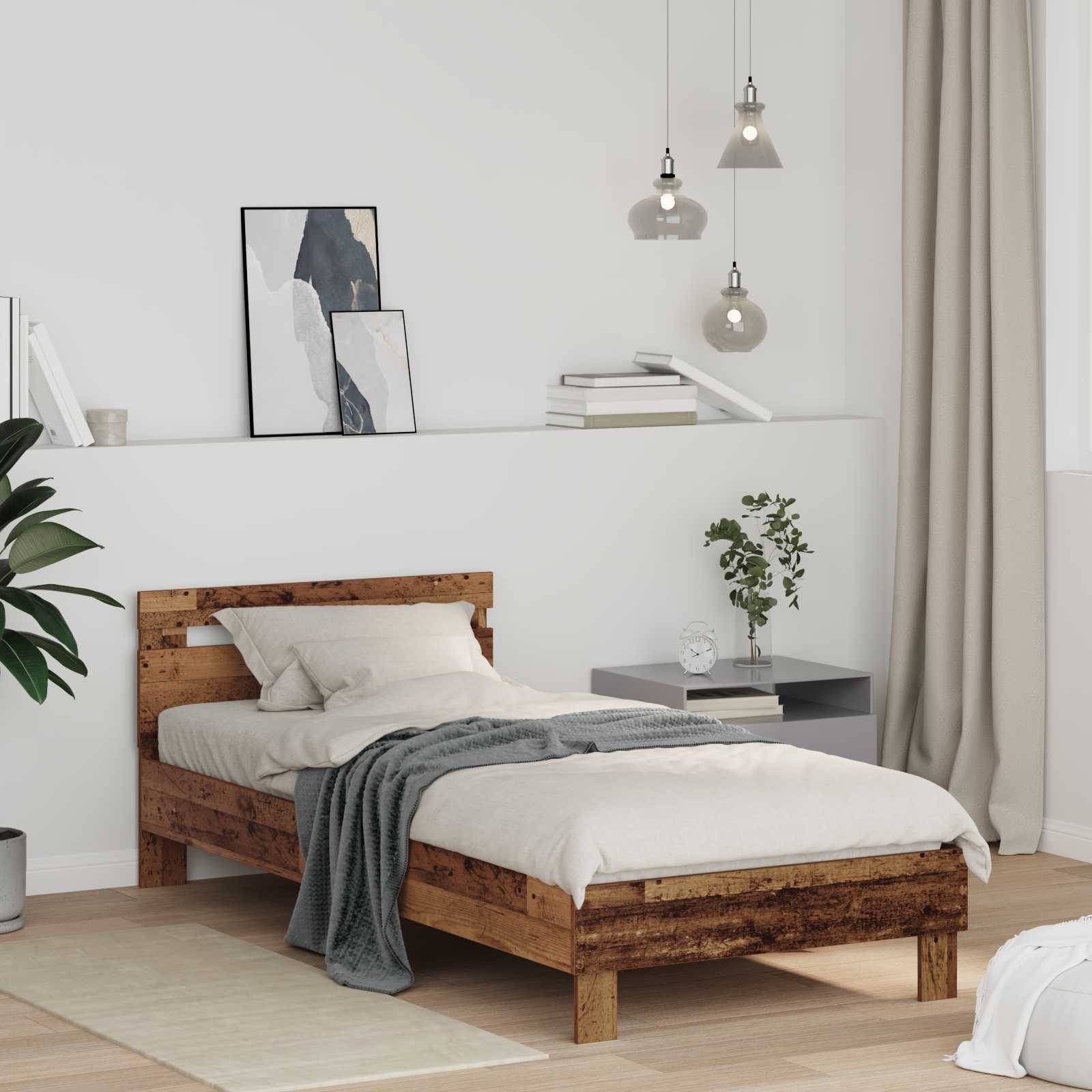 Ein modernes Schlafzimmer mit einem rustikalen Holzbett, grauer Bettwäsche, abstrakter Kunst, einem kleinen Nachttisch mit Büchern und einer Pflanze sowie hängenden Pendelleuchten.