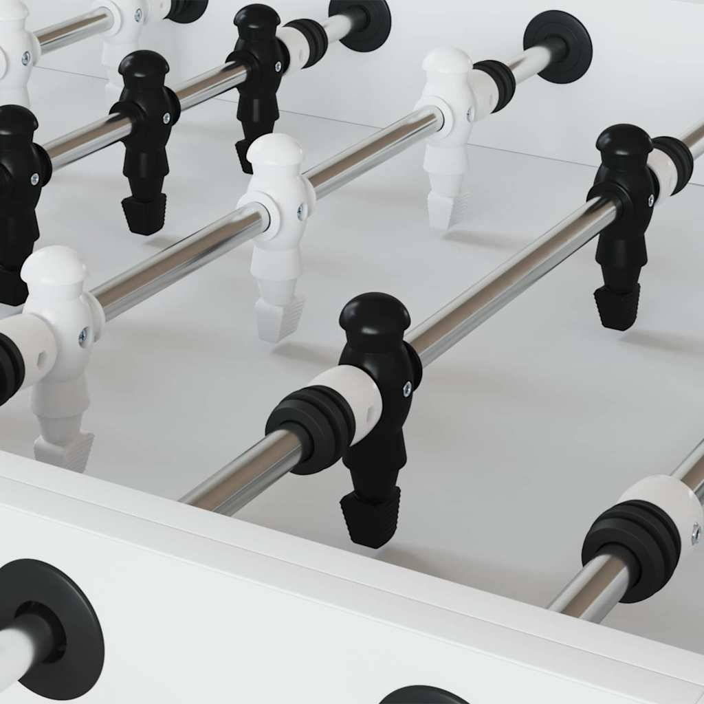 Ein Tischfußballtisch mit schwarzen und weißen Spielerfiguren, die an Metallstangen angeordnet sind, aus einem nahen Winkel aufgenommen und den Spielaufbau hervorhebend.