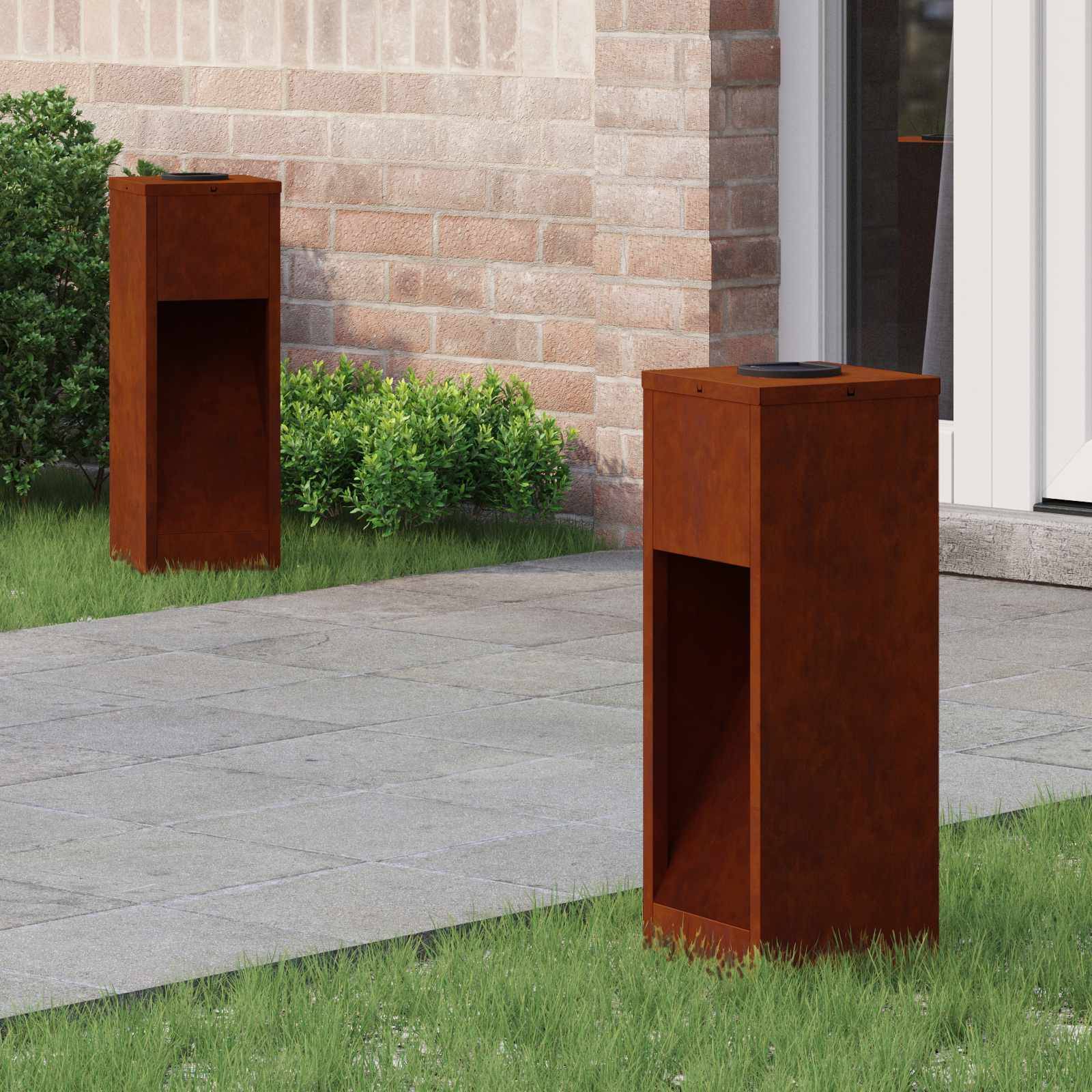 Zwei hölzerne Außenlautsprecher auf einem Steinweg in einem Garten, mit einer Backsteinmauer und Sträuchern im Hintergrund.