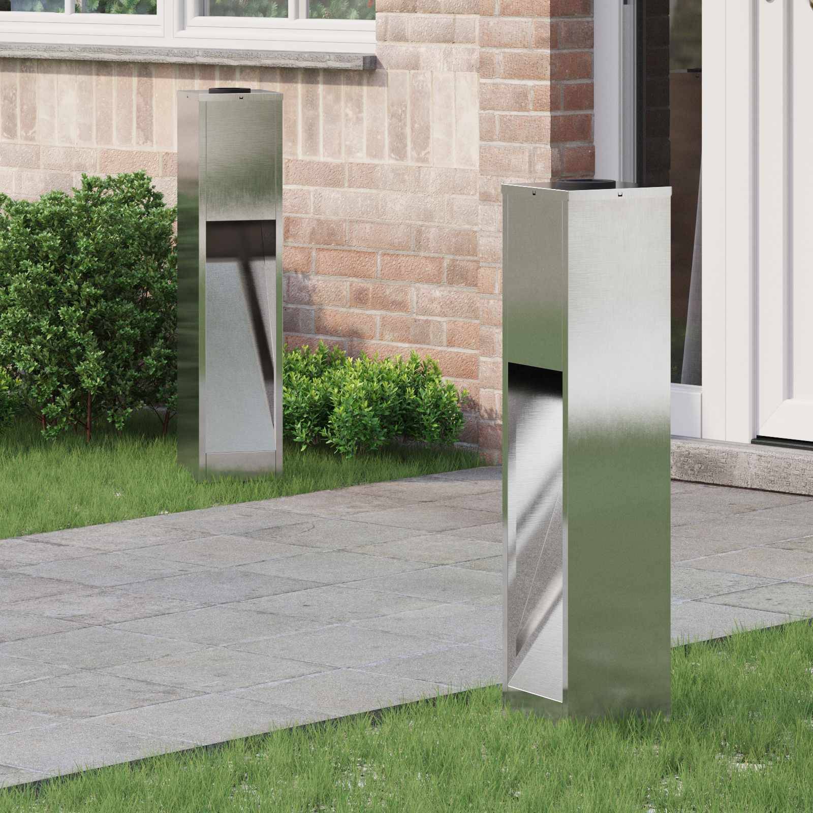Eine moderne Briefkasten mit Edelstahl-Finish steht an der Ziegelwand eines Hauses. In der Nähe sind gepflegte Sträucher und ein Fenster zu sehen.