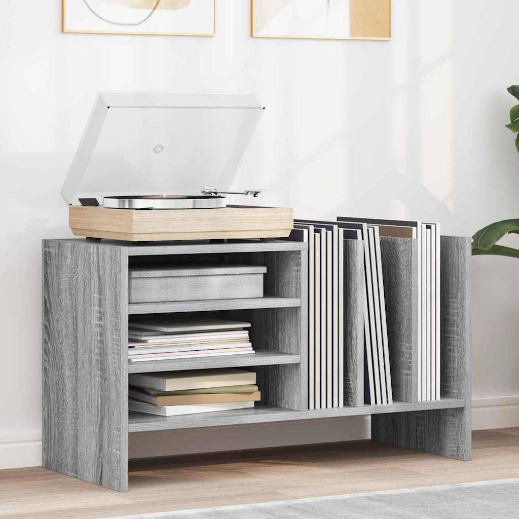 Ein grauer Holzregal trägt einen Plattenspieler mit offener Abdeckung oben, mehrere Schallplatten rechts daneben sowie Bücher und kleine Gegenstände auf den Regalen.