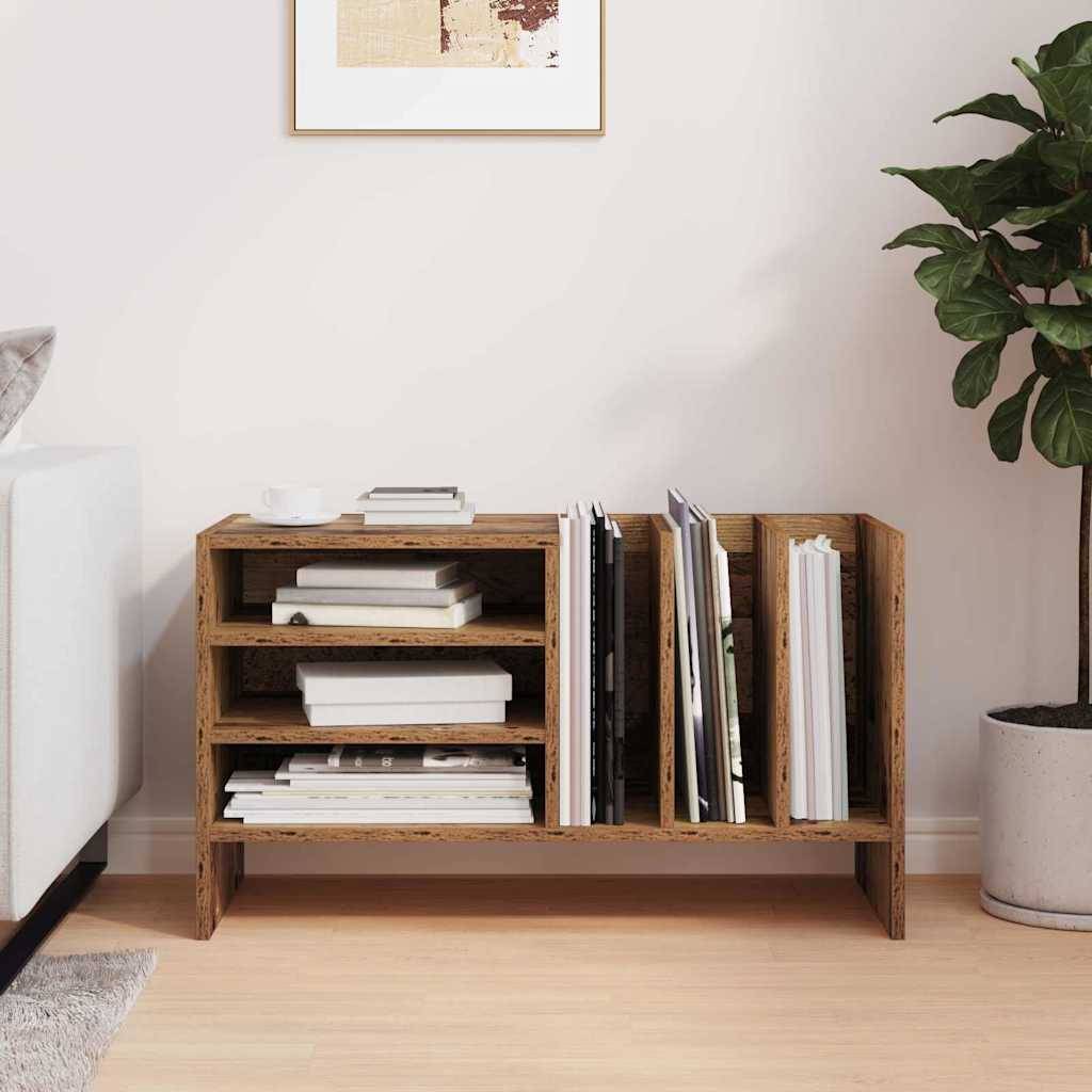 Ein kleines Holzregal steht an einer hellen Wand und trägt Bücher und Zeitschriften. Eine Zimmerpflanze sitzt rechts daneben und bringt etwas Grün in den Raum.