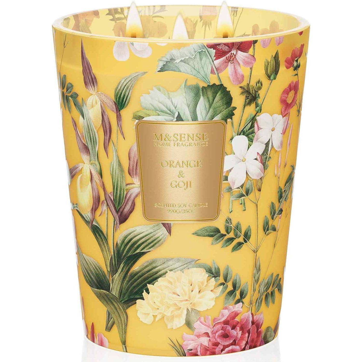 Eine gelbe, mit Blumenmuster versehene Kerze mit drei Dochten, auf einer zentralen Plakette in Gold mit der Aufschrift 