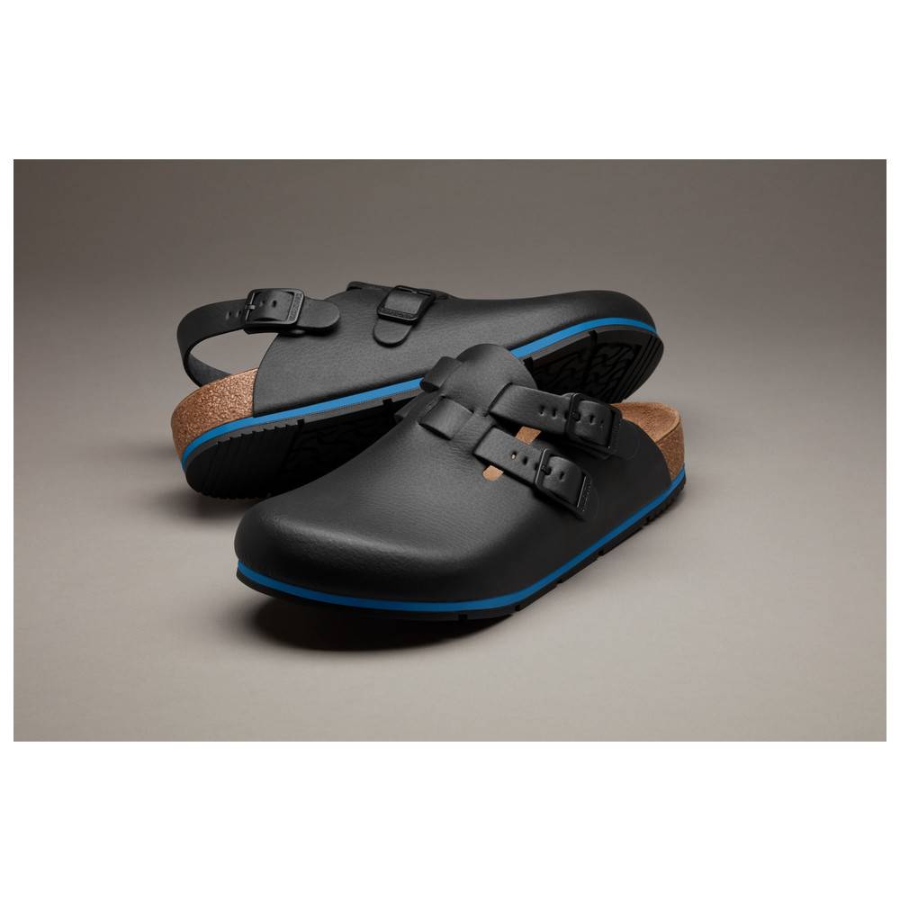 Zwei schwarze Slipper mit blauen Sohlen und verstellbaren Riemen, ausgestattet mit Korkfußbetten, auf einem neutralen Hintergrund präsentiert.