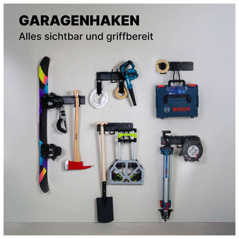 GARAGENHAKEN: Alles sichtbar und griffbereit. Verschiedene Werkzeuge und Ausrüstungsgegenstände, einschließlich eines Snowboards, einer Axt und einer Schaufel, an Haken aufgehängt.