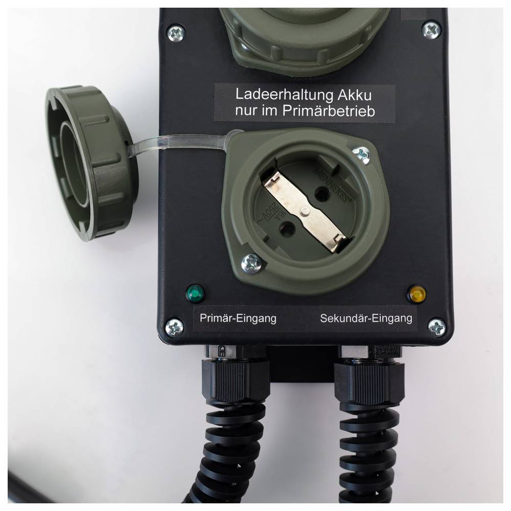Ein schwarzes Elektropanel mit zwei grauen Steckdosen, beschriftet mit 'Primär-Eingang' und 'Sekundär-Eingang'. Darüber steht der Text 'Ladeerhaltung Akku nur im Primärbetrieb'.