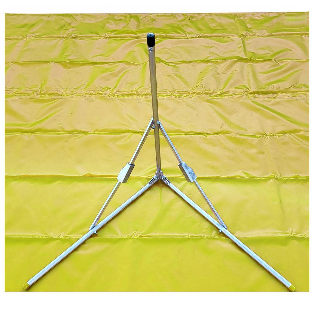 Ein gefalteter Metallstativ, der auf einer gelben, strukturierten Oberfläche liegt.