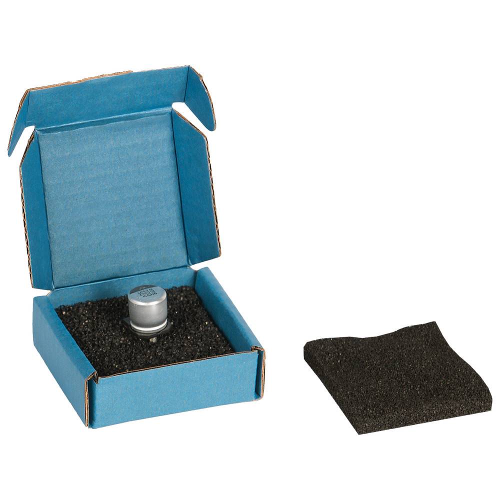 Ein kleines Metallobjekt in einer blauen Pappschachtel mit schwarzer Schaumstoffpolsterung im Inneren. Ein weiteres Stück schwarzen Schaums liegt außerhalb der Schachtel.