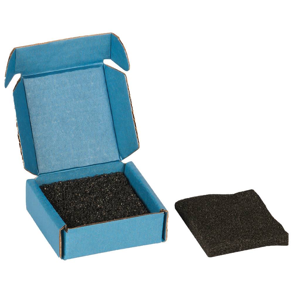 Geöffnete blaue Kartonbox mit schwarzem Schaumstoffeinsatz und einem separaten Schaumstoffstück daneben.