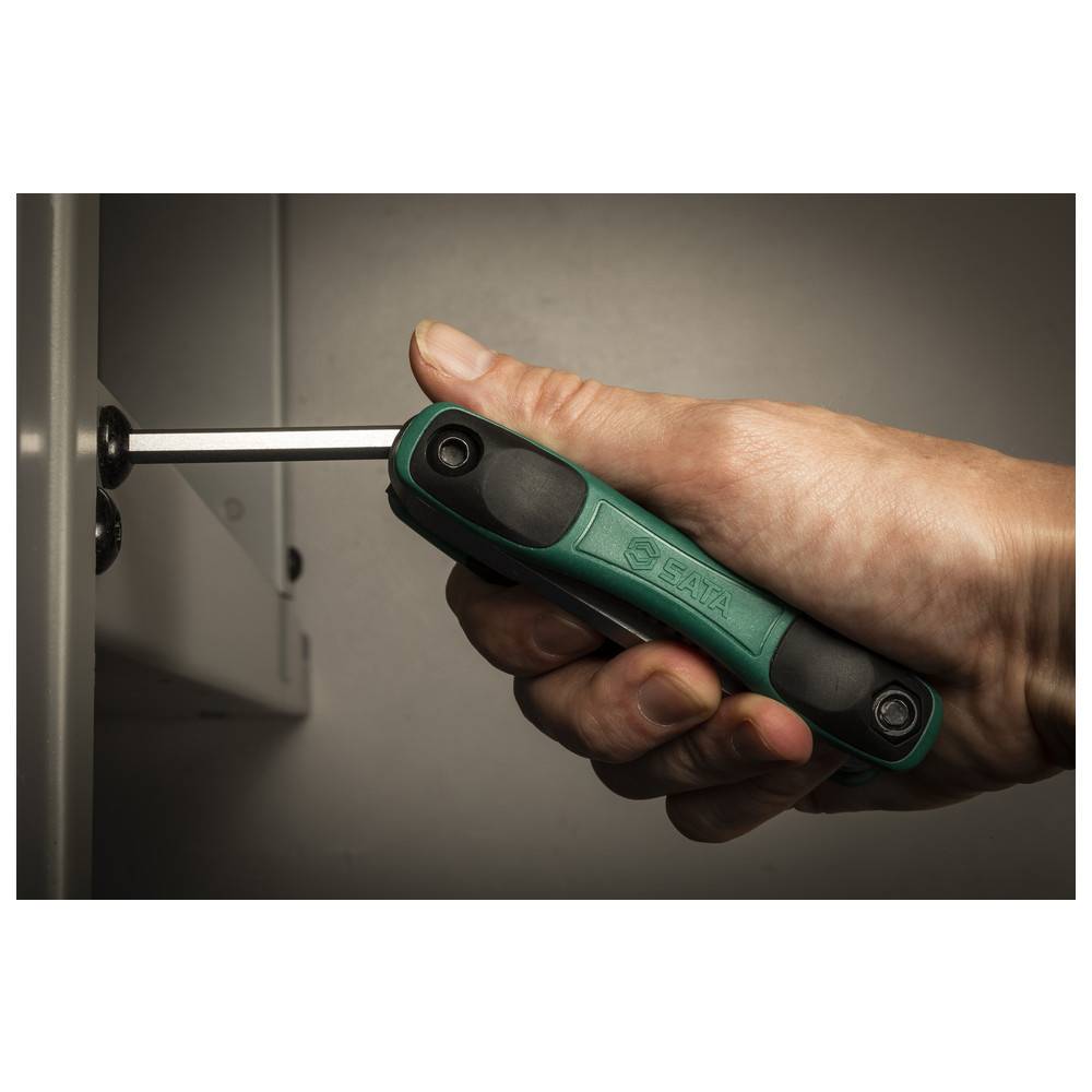 Eine Hand benutzt einen grün-schwarzen Schraubendreher, um eine Schraube auf einer Metalloberfläche festzuziehen und demonstriert dabei die Verwendung eines Werkzeugs und eine Grifftechnik.