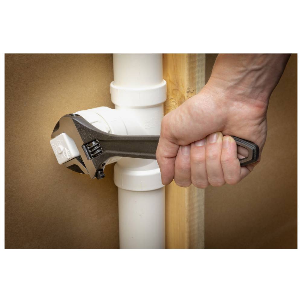 Eine Hand justiert eine Rohrverschraubung mit einem Schraubenschlüssel und demonstriert dabei die Wartung der Sanitärinstallation.