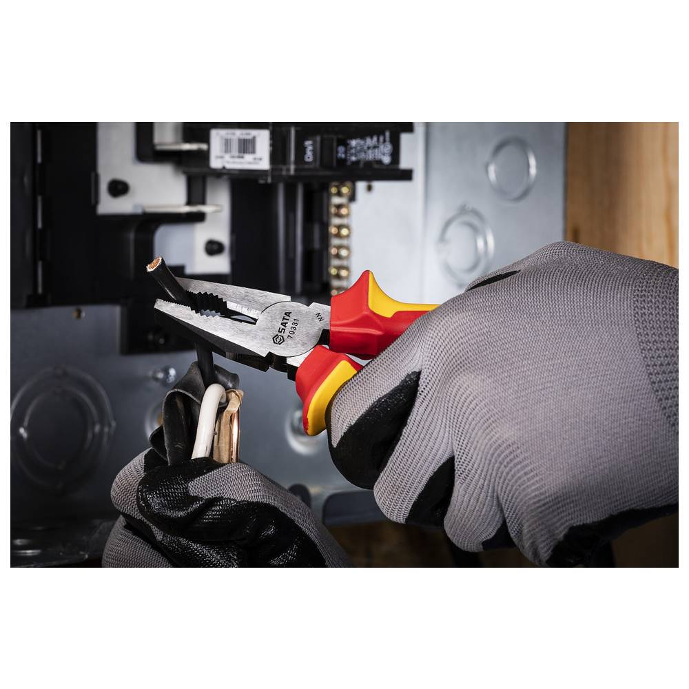 Eine Person mit Handschuhen verwendet isolierte Zange, um elektrische Kabel in der Nähe eines Sicherungskastens auszuschlachten, wobei Sicherheit bei elektrischen Arbeiten betont wird.