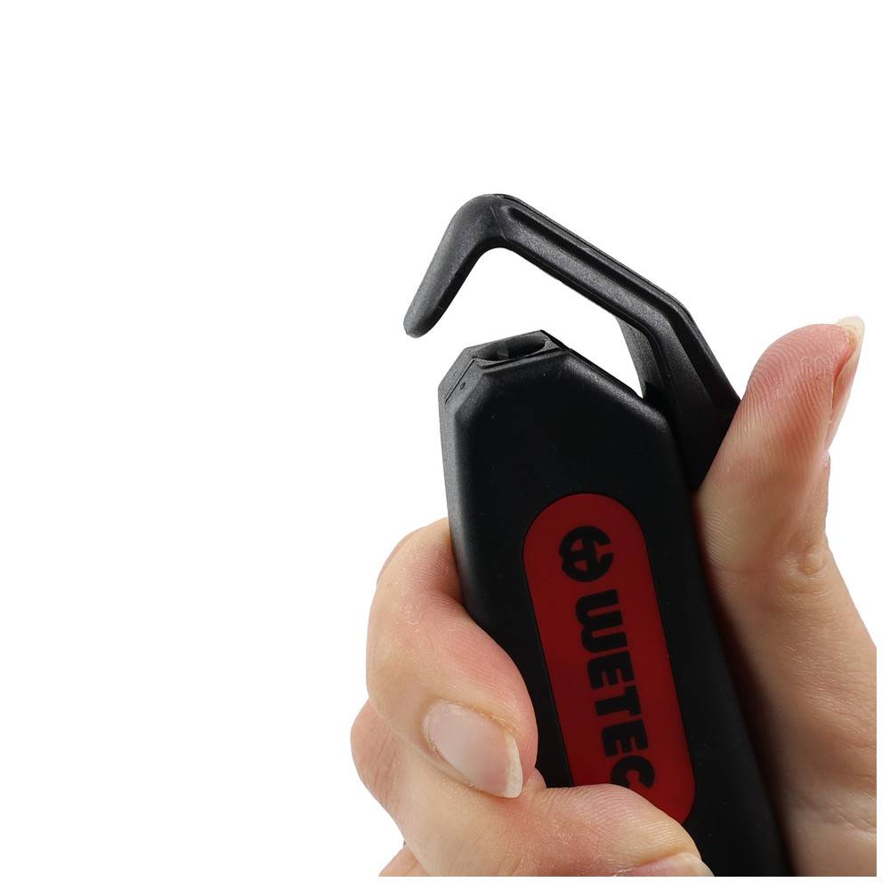 Eine Hand hält ein schwarzes und rotes Werkzeug mit einem gehakten Ende, beschriftet mit 'WETEC', was darauf hindeutet, dass es für bestimmte technische Aufgaben oder Reparaturen entwickelt wurde.