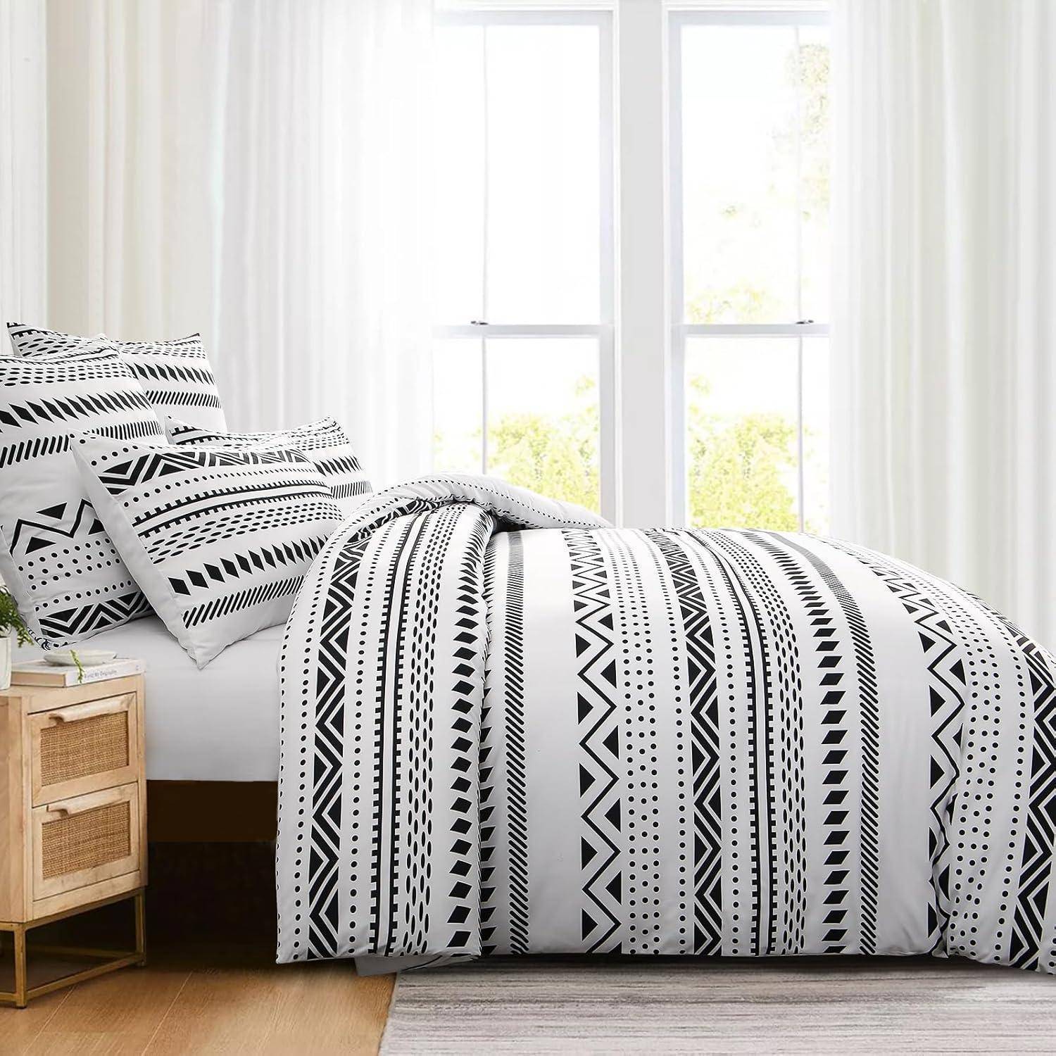 Ein Schlafzimmer mit einem Bett, das eine schwarz-weiße geometrisch gemusterte Bettdecke und Kissen aufweist, neben einem Holznachttisch und großen Fenstern.