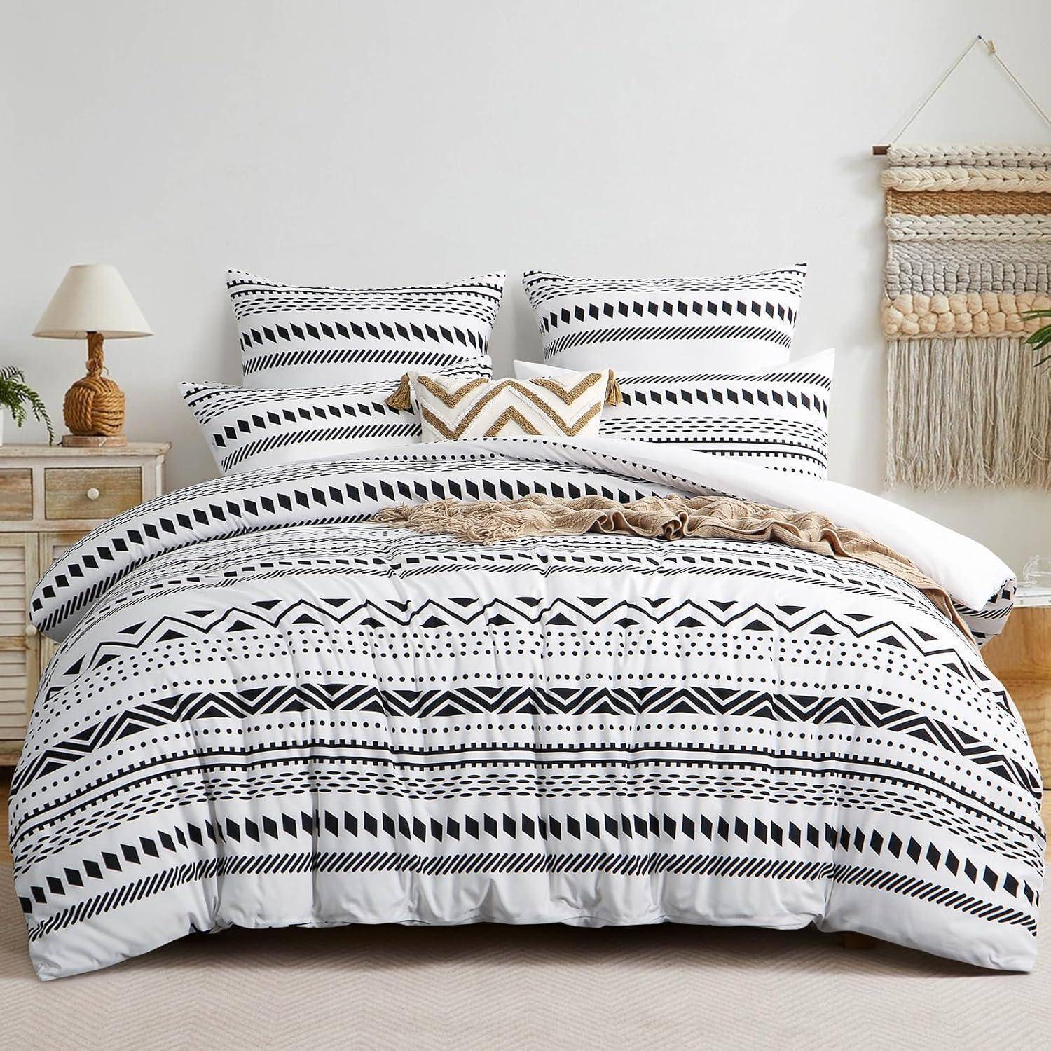 Ein Bett mit schwarz-weiß gemusterten geometrischen Bettwäsche, dekorativen Kissen, einem Holz-Nachttisch mit einer Lampe und Wandkunst darüber.