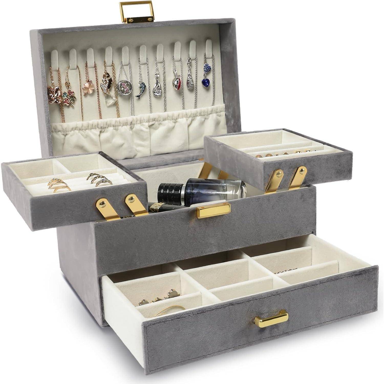 Eine graue Schmuckschatulle mit offenen Fächern, die Ringe, Ohrringe und Accessoires enthält. Der Deckel zeigt hängende Ohrringe.