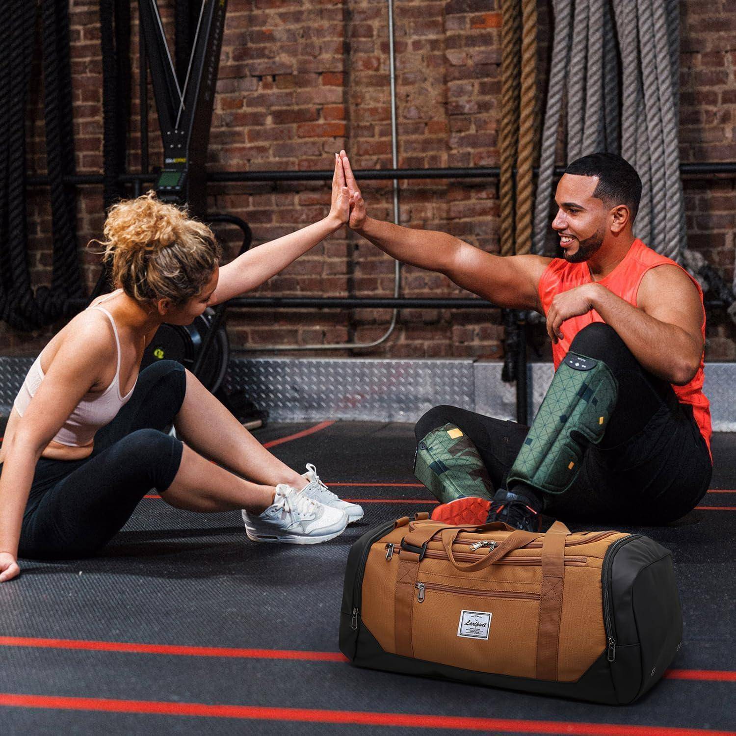 Eine Frau und ein Mann, beide in Sportkleidung, sitzen auf dem Boden eines Fitnessstudios und geben sich ein High Five. Eine braune Sporttasche befindet sich im Vordergrund.