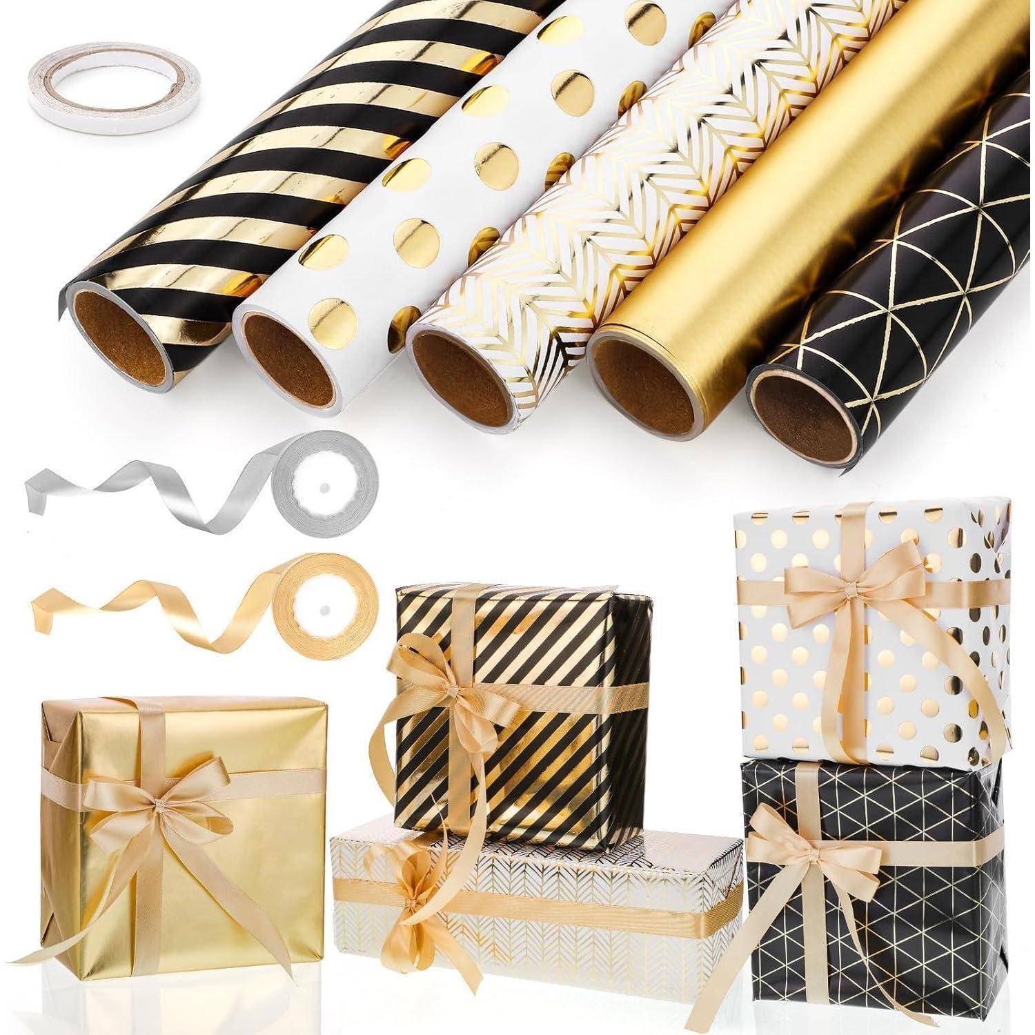 Geschenkverpackungsset mit Rollen gemusterten Papiers in Gold, Schwarz und Weiß, Band und mit Schleifen verzierten Geschenkkartons.
