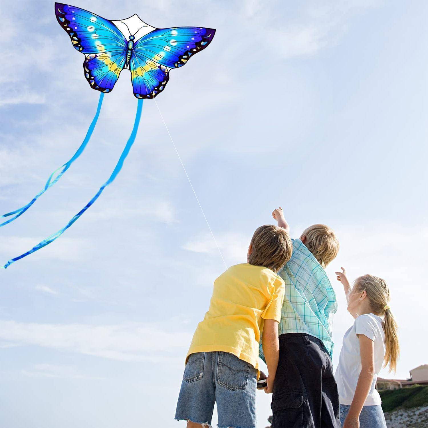 Eine Gruppe von Menschen beobachtet einen bunten, schmetterlingsförmigen Drachen, der an einem klaren Tag hoch am Himmel fliegt.