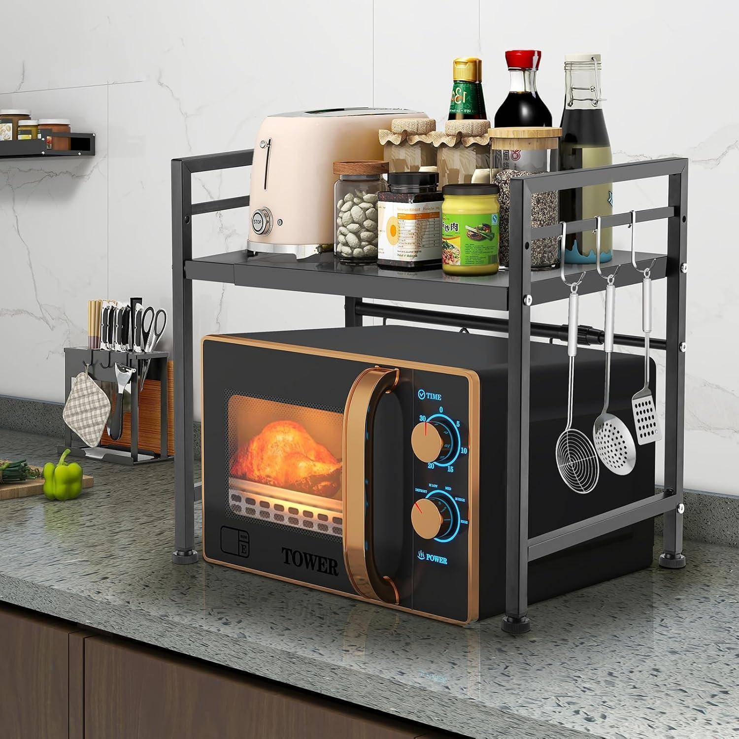 Eine Mikrowelle auf einer Küchenarbeitsplatte, umgeben von einem Metallregal mit Gewürzen, einem Toaster und Gläsern. Kochutensilien hängen seitlich.