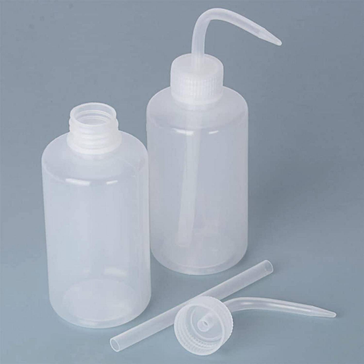 Zwei transparente, Plastikquetschflaschen mit spitzen Ausgüssen. Eine steht aufrecht, geschlossen, und die andere liegt mit abgenommenem Deckel.
