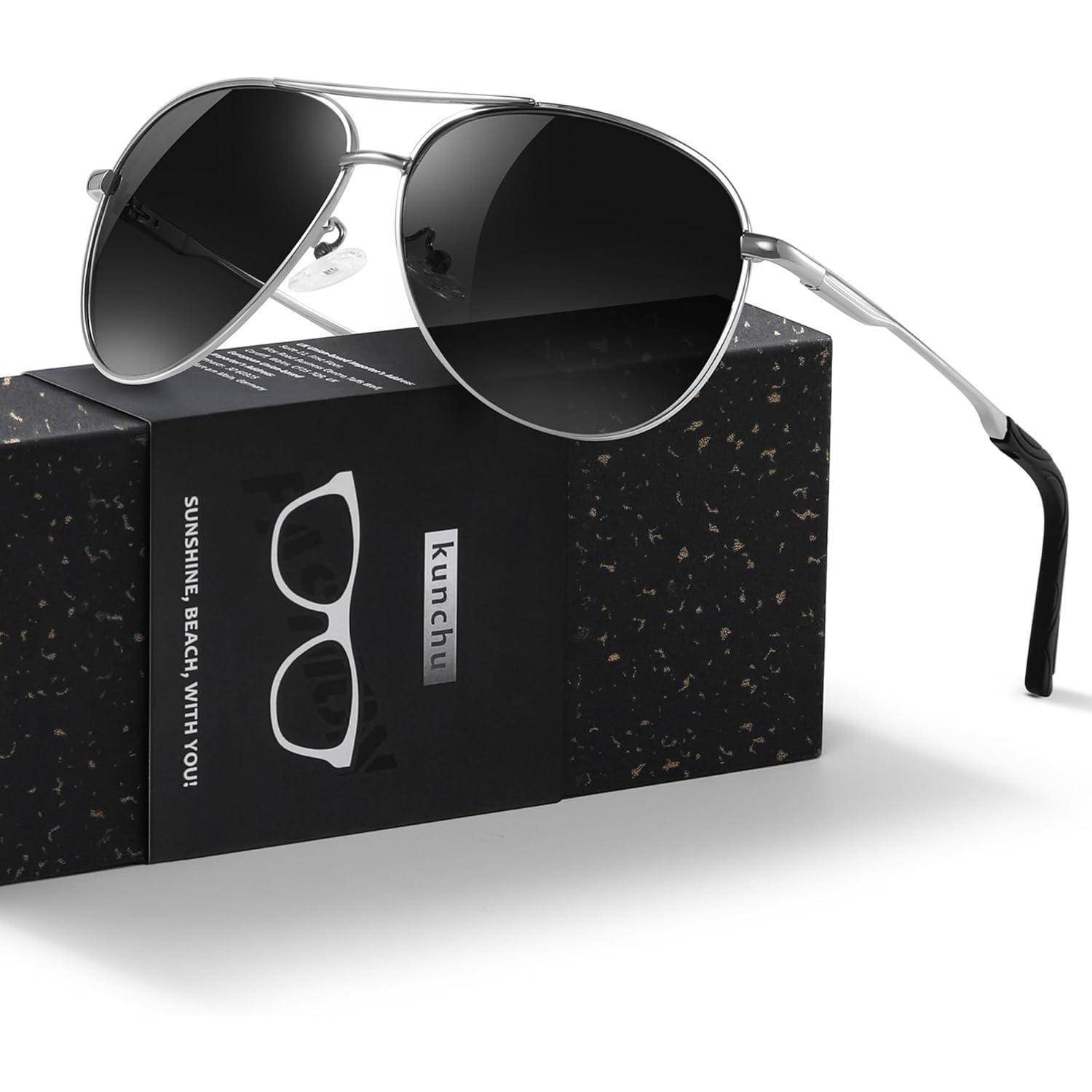 Eine Sonnenbrille mit silbernem Rahmen und dunklen Gläsern liegt auf einer schwarzen, gesprenkelte Verpackungsschachtel. Die Schachtel trägt die Aufschrift 