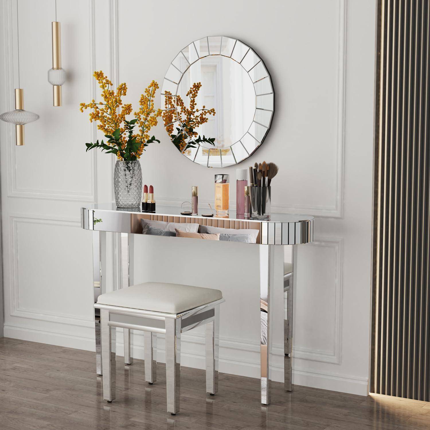 Eine schicke Schminktisch-Einrichtung mit einem Spiegel, goldgerahmten Blumen, dekorativen hängenden Leuchten und einem gepolsterten Hocker. Das Setting ist elegant und modern.