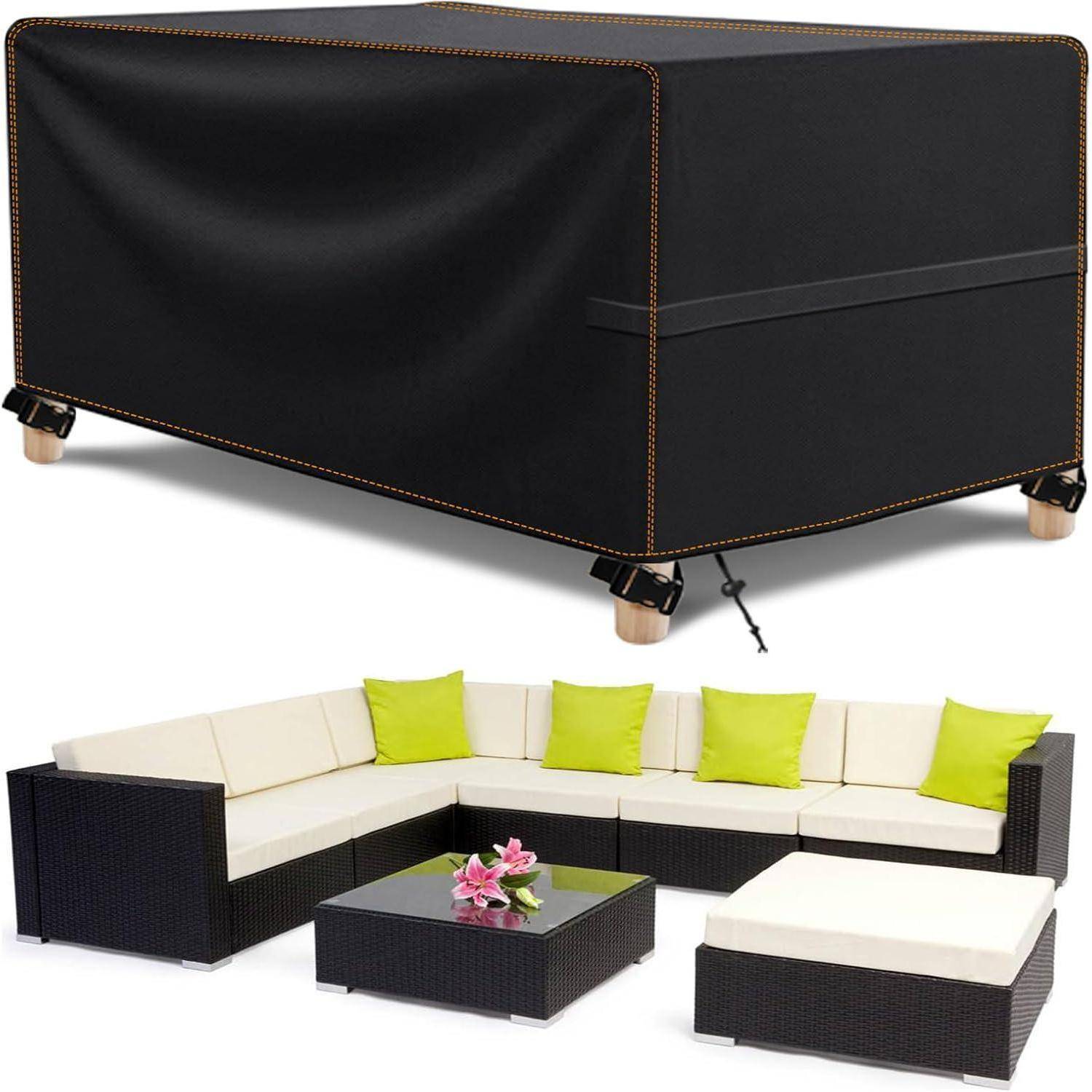 Eine schwarze Abdeckung drapiert über Terrassenmöbeln, einschließlich einer Sitzgruppe mit weißen Kissen und grünen Dekokissen sowie einem Couchtisch mit rosa Blumen.