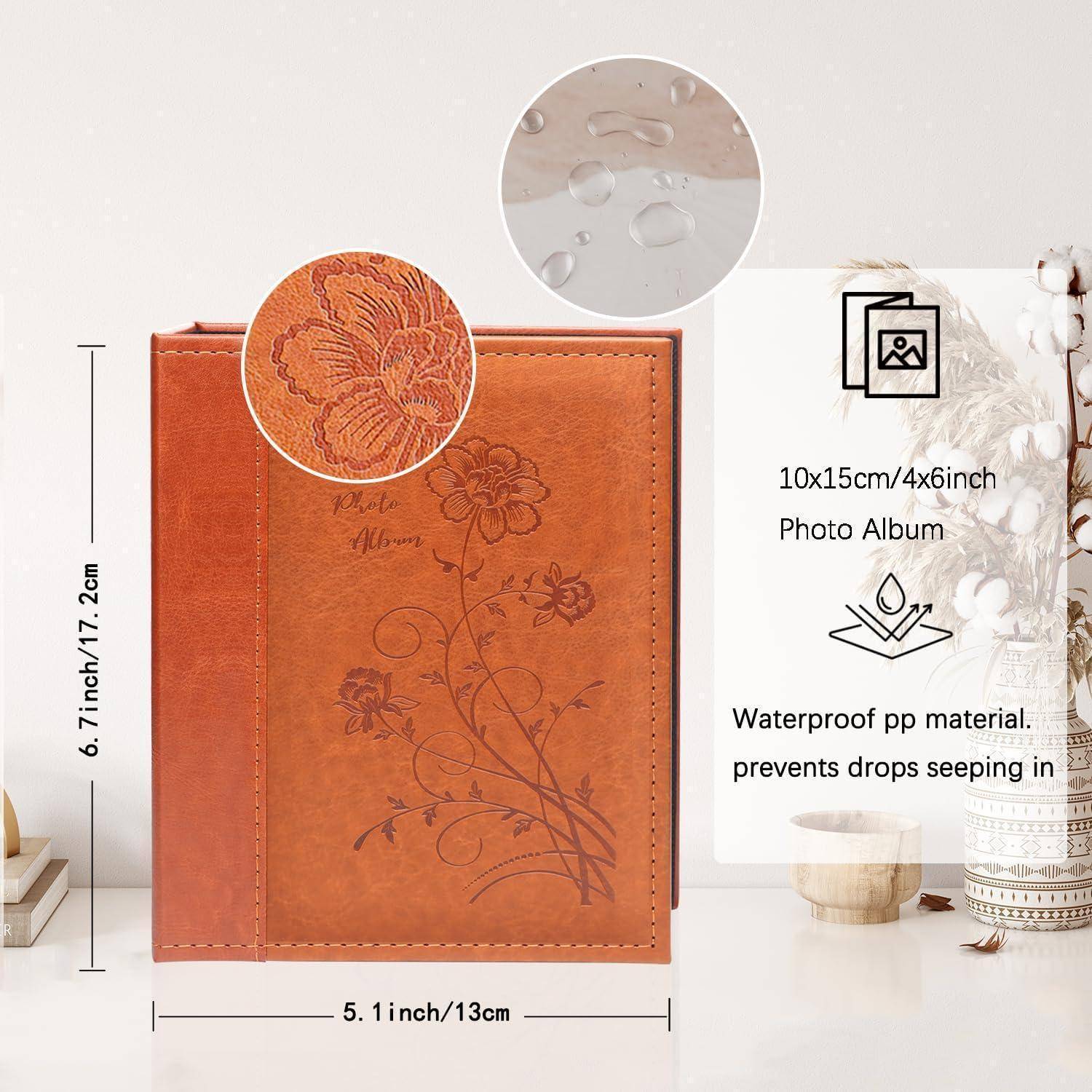 Ein braunes 10x15 cm Fotoalbum mit Blumenprägung auf dem Einband, aus wasserfestem Material, auf einem Tisch mit Dekoration platziert.