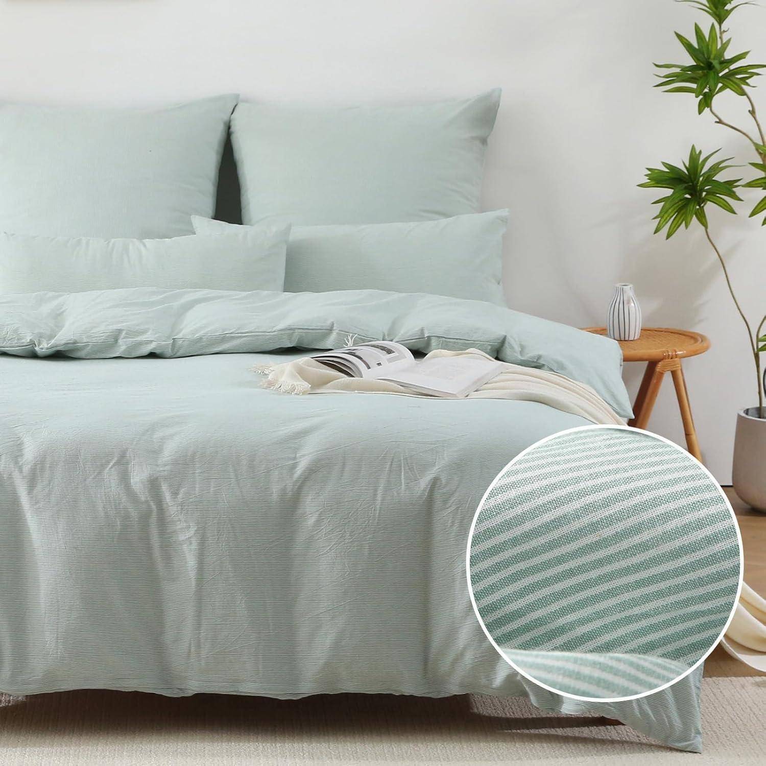 Ein ordentlich gemachtes Bett mit hellgrünen Kissen und Bettwäsche. Eine kleine Pflanze und ein Tisch mit einer Vase stehen in der Nähe. Eine Nahaufnahme einer Stofftextur ist zu sehen.