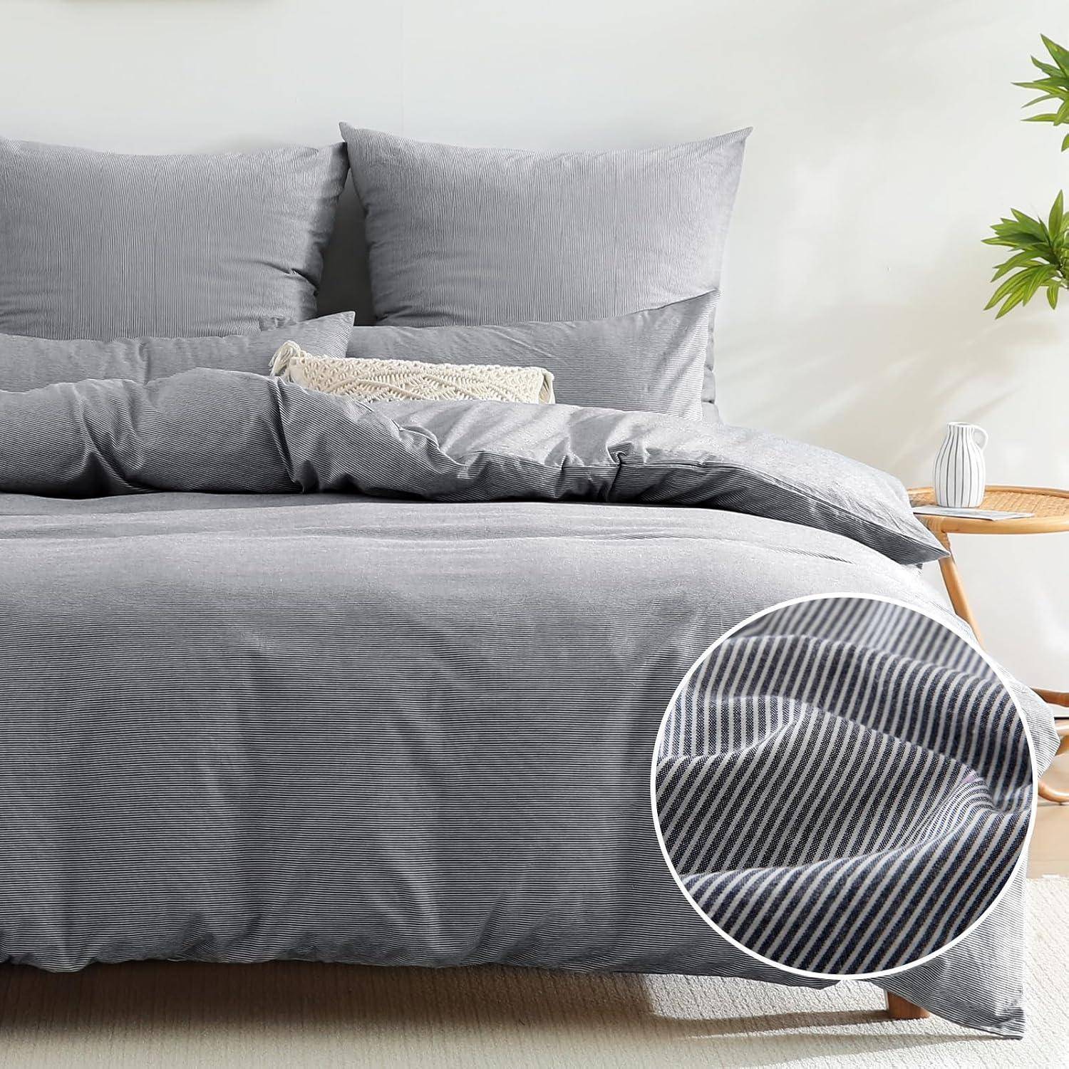Ein ordentlich gemachtes Bett mit grau gestreifter Bettwäsche, zwei großen Kissen und einem Zierkissen. Ein vergrößerter Kreis zeigt die Stofftextur.