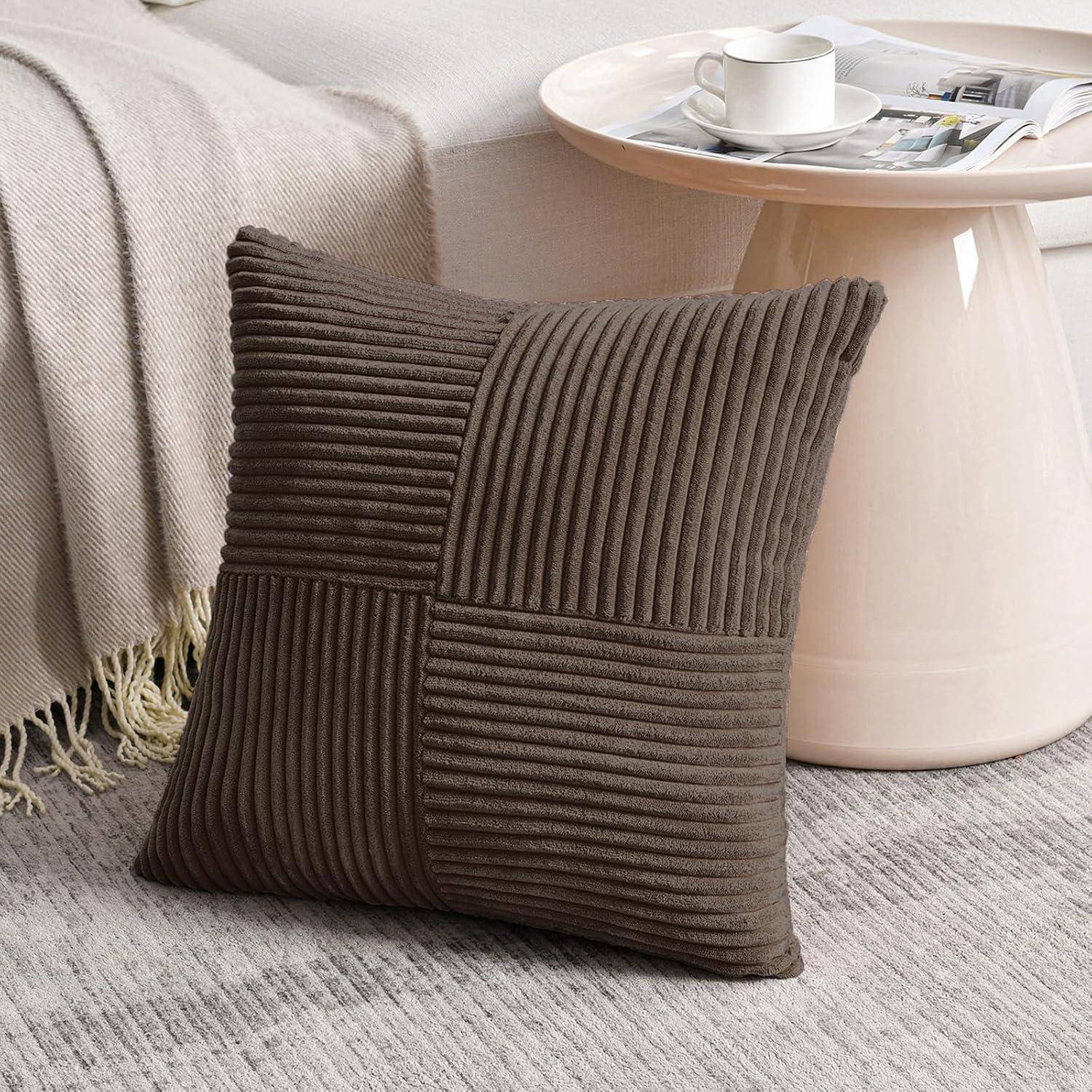 Ein braunes strukturiertes Kissen liegt auf einem teppichbelegten Boden neben einem Holzseitentisch mit einer weißen Teetasse und Untertasse sowie einer aufgeschlagenen Zeitschrift.