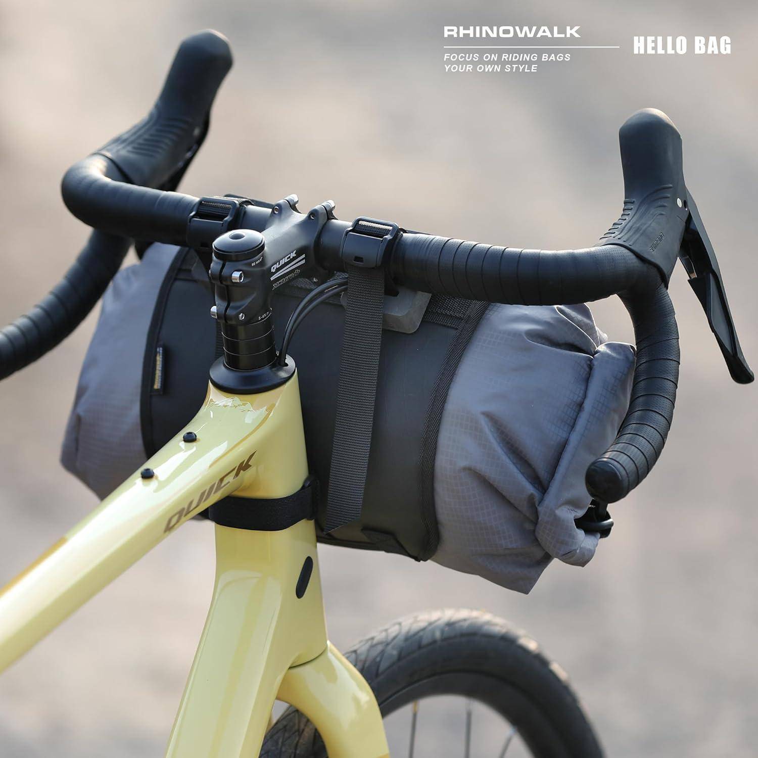 Ein gelbes Fahrrad mit einer aufgerollten grauen Tasche, die an den Lenkern befestigt ist und eine Transportlösung für Fahrradausflüge präsentiert.