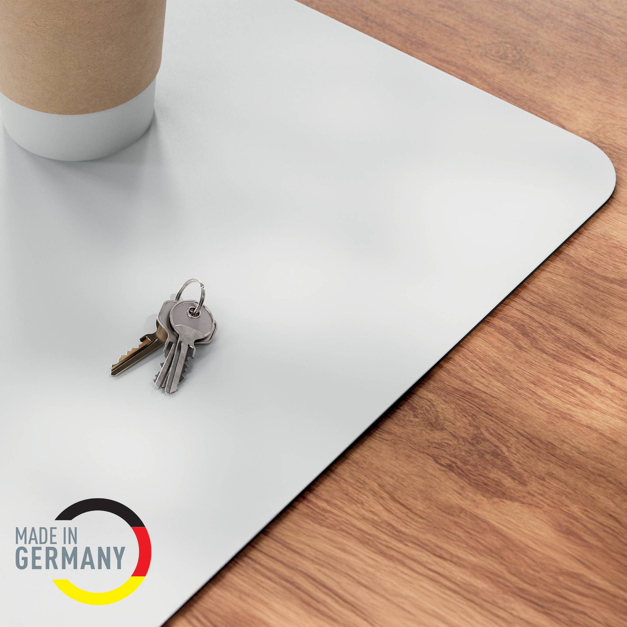 Schlüssel auf einer hellgrauen Schreibunterlage neben einer Kaffeetasse, mit einem 