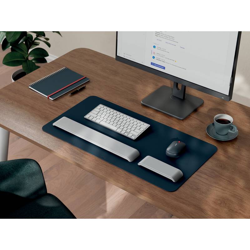 Ein moderner Arbeitsplatz mit einem Holzschreibtisch, auf dem ein Computermonitor, Tastatur, Maus, Notizbuch und eine Tasse Kaffee stehen, der eine organisierte und einladende Atmosphäre schafft.