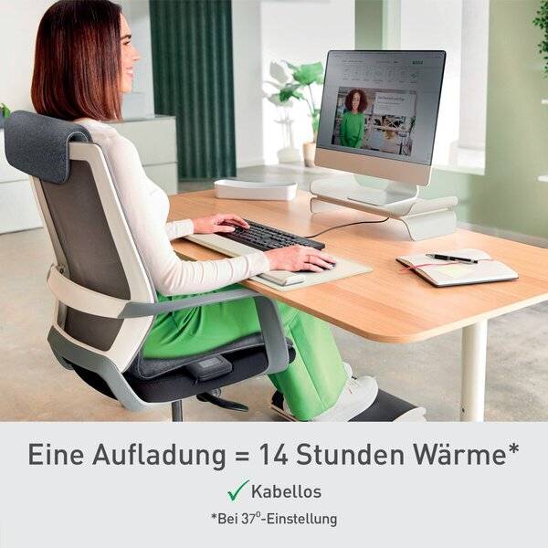 Frau nutzt einen Desktop-Computer an einem Schreibtisch; der deutsche Text darunter besagt „Eine Ladung = 14 Stunden Wärme*