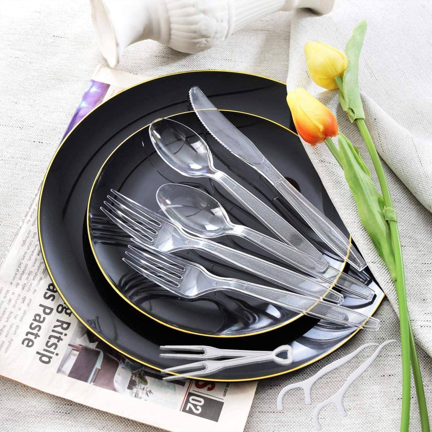Schwarze Keramikteller mit silbernem Besteck auf einer Zeitung; farbenfrohe Tulpen und eine weiße Vase in der Nähe.