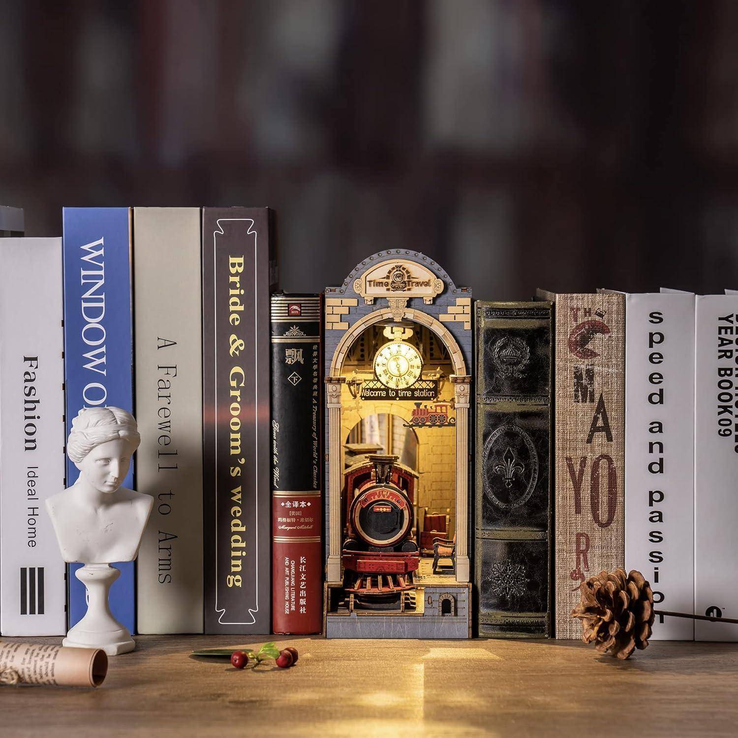 Bücher, die auf einem Regal aufgereiht sind, rahmen eine dekorative Miniaturszene ein, die einen Vintage-Zug darstellt und von einer leuchtenden, kunstvollen Uhr beleuchtet wird.