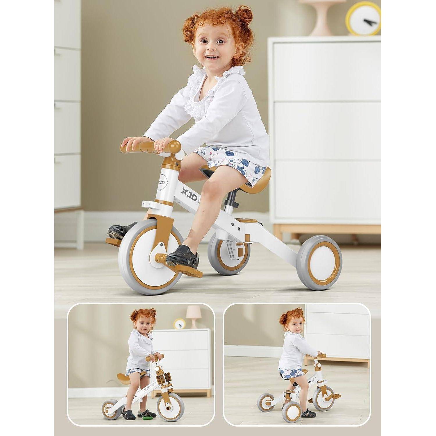 Ein kleines Kind mit lockigen roten Haaren fährt lächelnd ein kleines weißes Dreirad im Innenraum. Der Raum ist mit helltonigen Möbeln und Dekorationen ausgestattet.